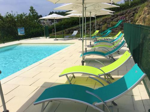 - une rangée de chaises et de parasols à côté de la piscine dans l'établissement Hôtel des Barrages, à Brommat