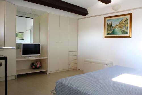 a white bedroom with a bed and a television at Residenza le Saline in Comacchio