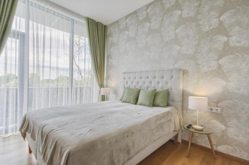 sypialnia z dużym łóżkiem i dużym oknem w obiekcie Luxury Apartments w Druskienikach