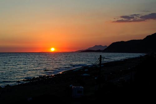 a sunset over the ocean with the sun setting at Hotel Loukas Vrachos in Paralia Vrachou