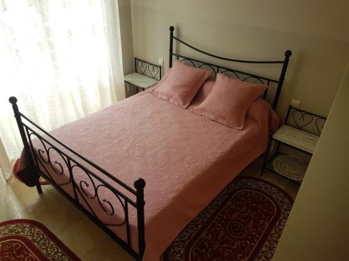 a bedroom with a bed with pink pillows and a window at Mehdia plage in Kenitra