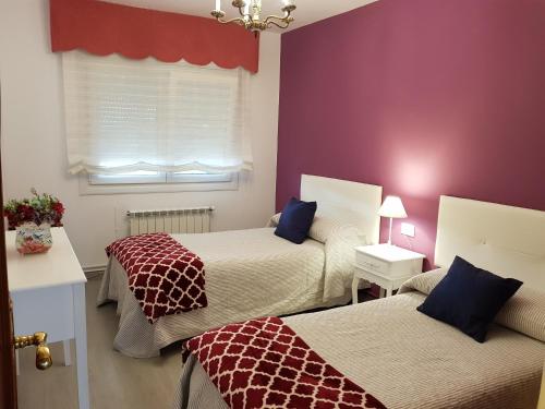 2 camas en una habitación con paredes de color púrpura y ventana en Apartamento Las Hermanas, en Pontevedra