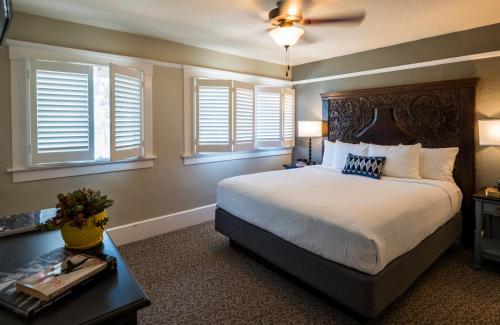 a bedroom with a bed and a table and windows at El Cordova in San Diego