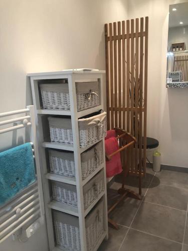 une étagère blanche avec des paniers dans une pièce dans l'établissement APPARTEMENT T2 SUR PATIO, à Ganges