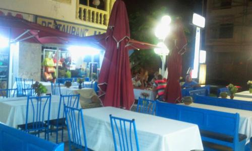 a restaurant with tables and chairs and a red umbrella at Hotel Hamilton in Hammamet