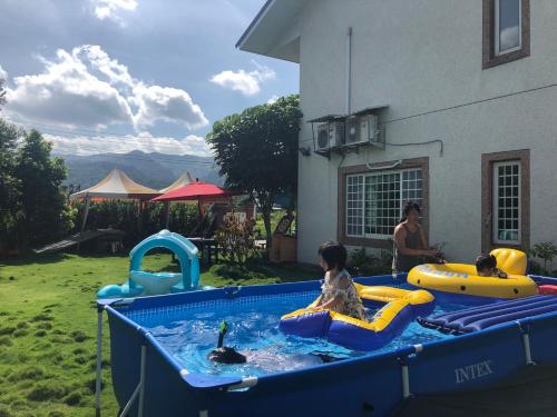 公館鄉的住宿－公館田庄二館，一名女子和两名儿童在游泳池玩耍