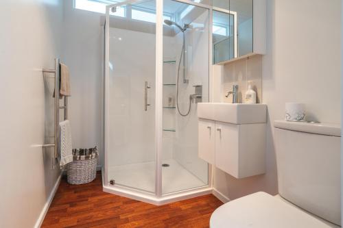 La salle de bains blanche est pourvue d'une douche et de toilettes. dans l'établissement Tikapa Moana Views, à Oneroa