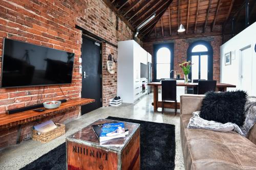 a living room with a brick wall with a large tv at The Terminus in Dunedin