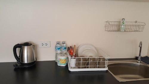 a kitchen counter with a sink and a dish drying rack at Condo C2 IMPACT in Nonthaburi