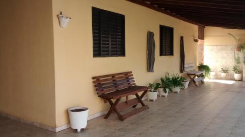 a bench sitting next to a wall with potted plants at Casa de Temporada Recanto Fazendinha in Olímpia