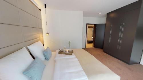 una camera con un grande letto bianco con cuscini blu di White Pearl Apartment 3.08 a Timmendorfer Strand