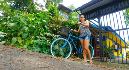 a woman standing on a sidewalk next to a bike at Cabinas Casa Dolce Vita in Puerto Viejo