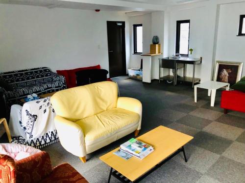 a living room with a yellow couch and a table at Izu Kansya in Atami