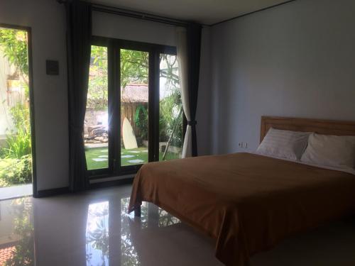 a bedroom with a bed and a large window at Bali Full Moon Guest House in Canggu