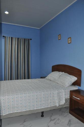 a bedroom with a bed with a blue wall at Hotel Casa Blanca in León