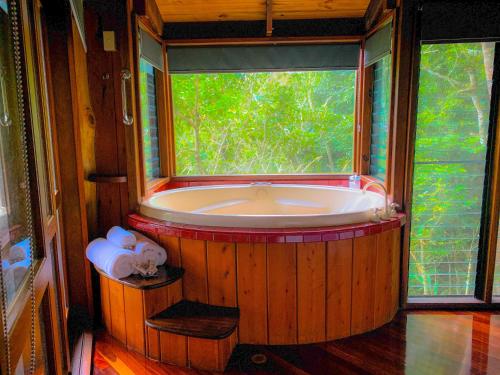 una gran bañera de madera en una habitación con ventana en Mt Quincan Crater Retreat, en Yungaburra