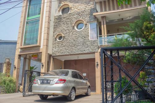 un coche plateado estacionado frente a una casa en RedDoorz Syariah near Pasar Modern Cikopo, en Karawang