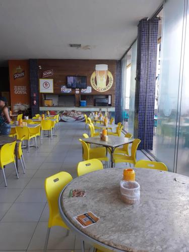une salle à manger avec des chaises et des tables jaunes dans un restaurant dans l'établissement Bahia Flat, à Salvador
