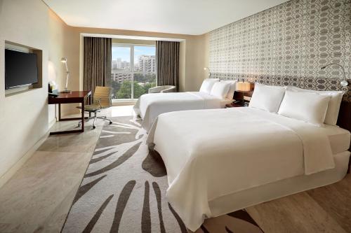a hotel room with two beds and a desk and a television at Crowne Plaza Dhaka Gulshan by IHG in Dhaka