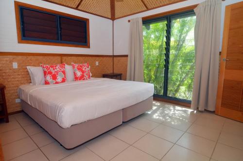 a bedroom with a bed and a large window at Island Magic Resort Apartments in Port Vila