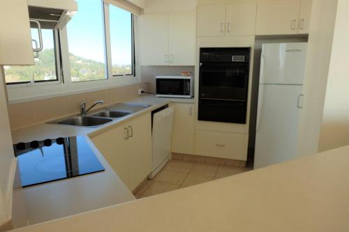 a kitchen with white cabinets and a sink and a refrigerator at Meridian Tower Kirra Beach in Gold Coast