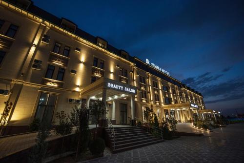 een hotelgebouw met 's nachts een bord bij Simma Hotel Spa & Waterpark in Tasjkent