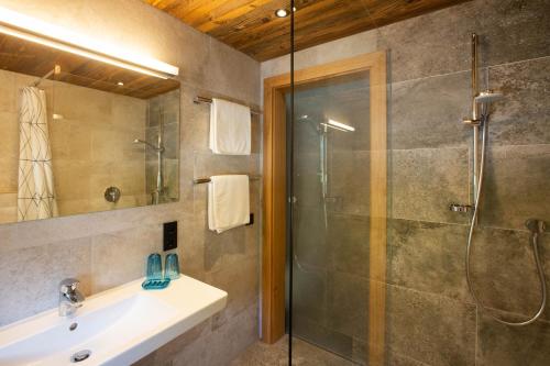 ein Bad mit einer Dusche und einem Waschbecken in der Unterkunft Midland in Sankt Anton am Arlberg