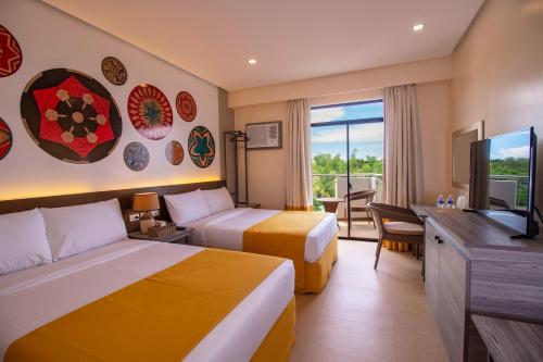 a hotel room with two beds and a flat screen tv at Bohol Shores in Panglao Island