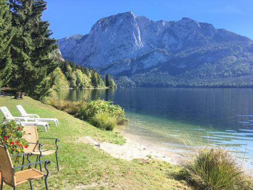 a row of chairs sitting on the shore of a lake at Hotel am See - Seeresidenz in Altaussee