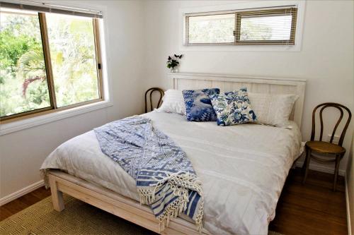 a bedroom with a bed with blue pillows and a window at Byron Marvell in Byron Bay