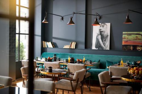 a restaurant with a green couch and tables and chairs at Hotel Victoria in Valence