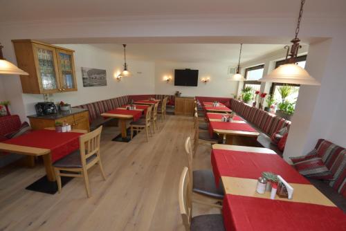 ヴァイセンゼーにあるHaus Binterの木製のテーブルと椅子、赤いテーブルが備わるレストラン