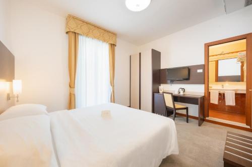 a hotel room with a white bed and a desk at Park Hotel Pineta Boutique Hotel in Caorle