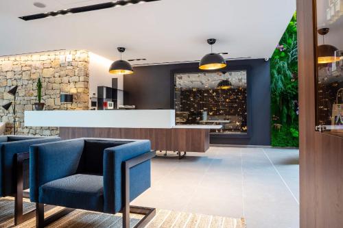 a lobby with blue chairs and a bar at Hôtel Sainte Victoire in Vauvenargues