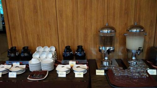a table with plates and cups and a coffee maker at Hotel Namira Syariah Pekalongan in Pekalongan