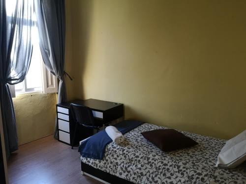 a bedroom with a bed and a desk and a window at Guesthouse Monsanto in Porto