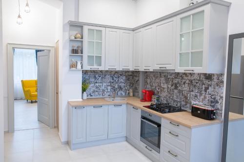 a kitchen with white cabinets and a sink at SUNNY NOVEMBER in Braşov