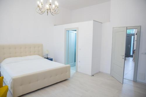 a white bedroom with a bed and a chandelier at SUNNY NOVEMBER in Braşov