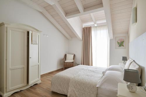 a white bedroom with a bed and a window at Agriturismo Casastella in Ceriale