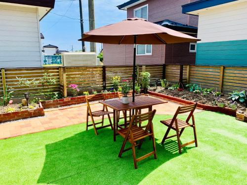 a table and chairs with an umbrella in a yard at Ecco's House エッコズハウス in Shiraoi