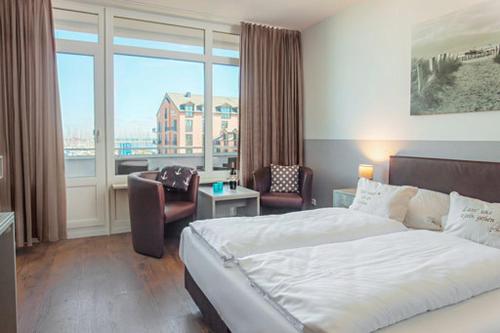 ハイリゲンハーフェンにあるKappen Plambeckのベッドと大きな窓が備わるホテルルームです。
