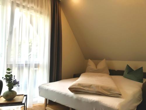 a bed in a room with a window with a white sheets at Pflugwirts Hotel und Gasthaus in Oberkirch