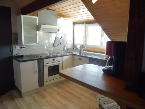 une cuisine avec des armoires blanches et un comptoir dans l'établissement La Mansarde de Clo, à Gérardmer