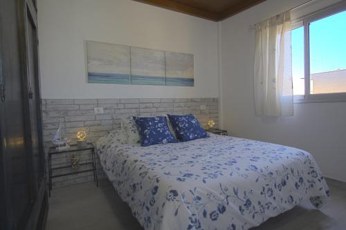 a bedroom with a bed with blue and white sheets and a window at ÁTICO LAS ALGAS in Granadilla de Abona