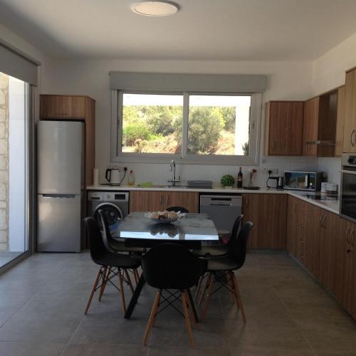 a kitchen with a table and chairs and a refrigerator at Pomos Idol Exceptional Beach Villa in Pomos
