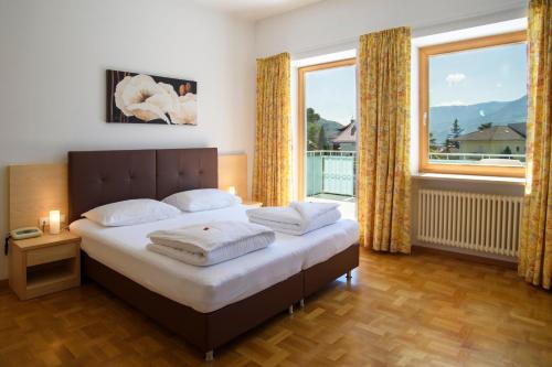 a bedroom with a bed and a large window at Hotel Filipinum in Merano