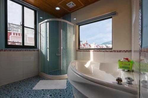 baño con bañera y ducha y 2 ventanas en Happiness Space, en Hengchun
