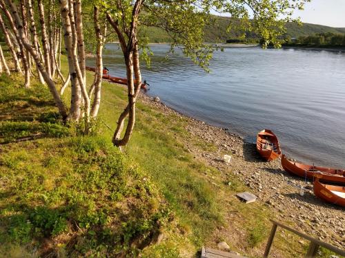 dwie łodzie siedzące na brzegu jeziora w obiekcie Vetsikon Leirintämökit w mieście Utsjoki