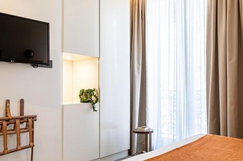 a bedroom with a tv on a wall next to a window at Hotel Le Friedland in Paris