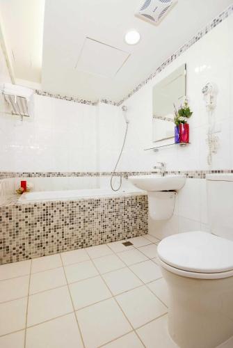 a bathroom with a toilet and a sink and a tub at The Metro Hotel - Taipei Branch in Taipei